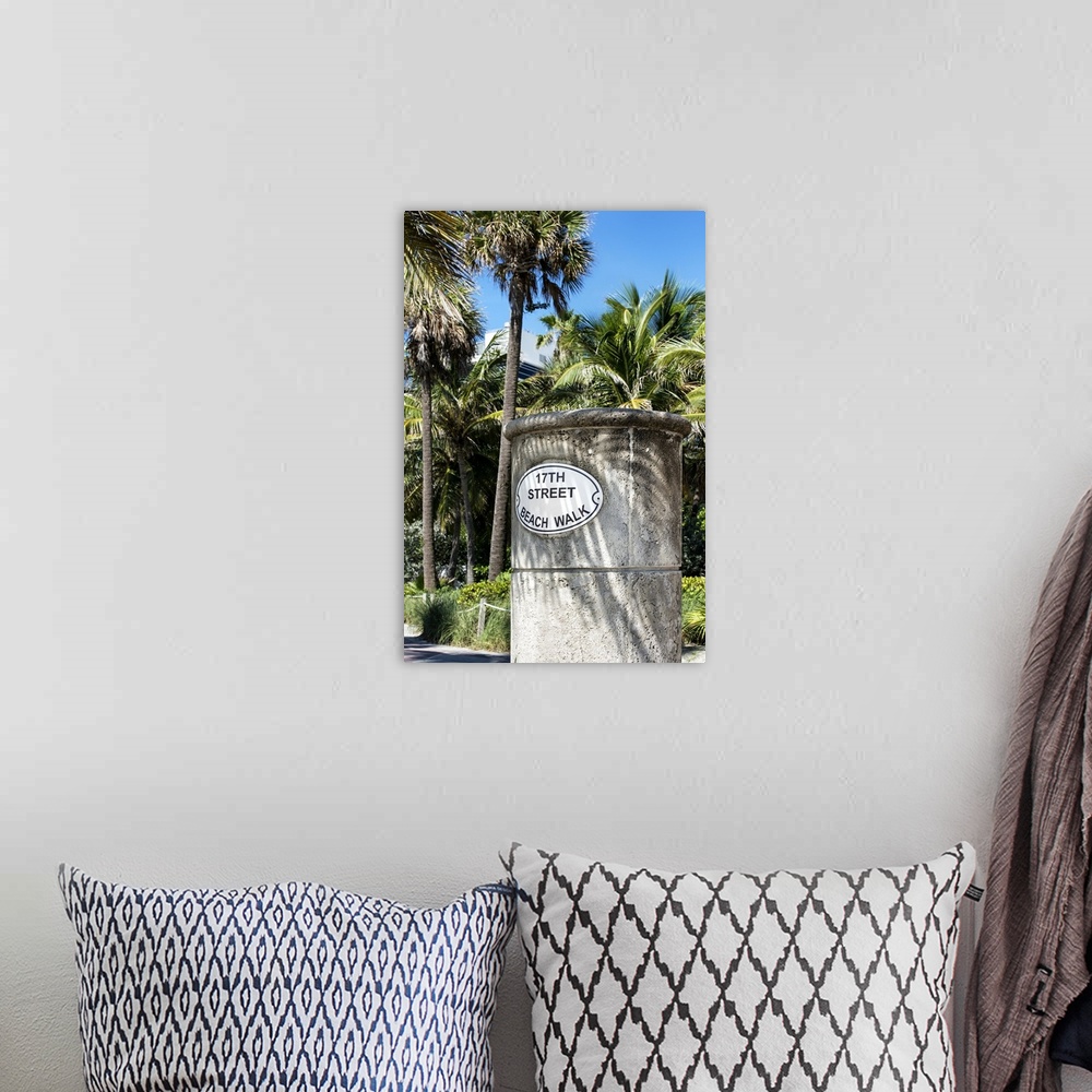 A bohemian room featuring A stone sign for the Beach Walk in Miami, shaded by palm trees.