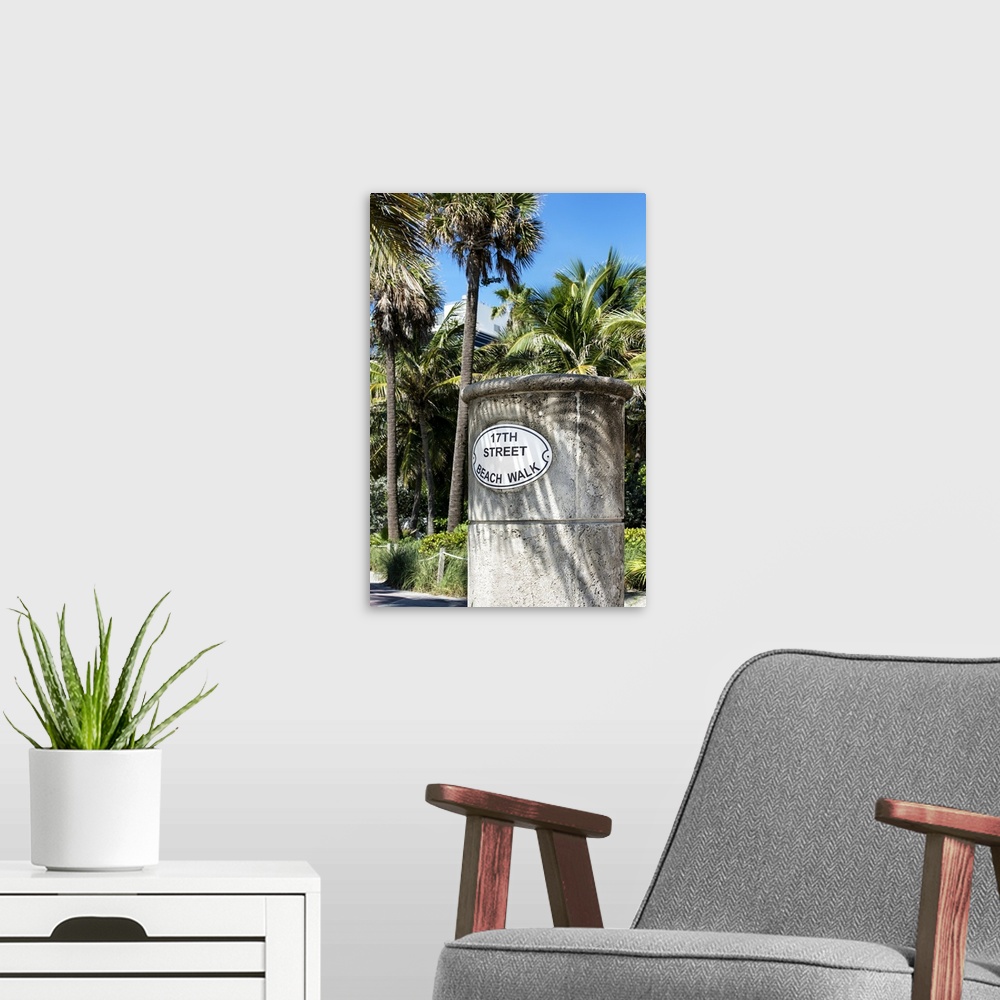 A modern room featuring A stone sign for the Beach Walk in Miami, shaded by palm trees.