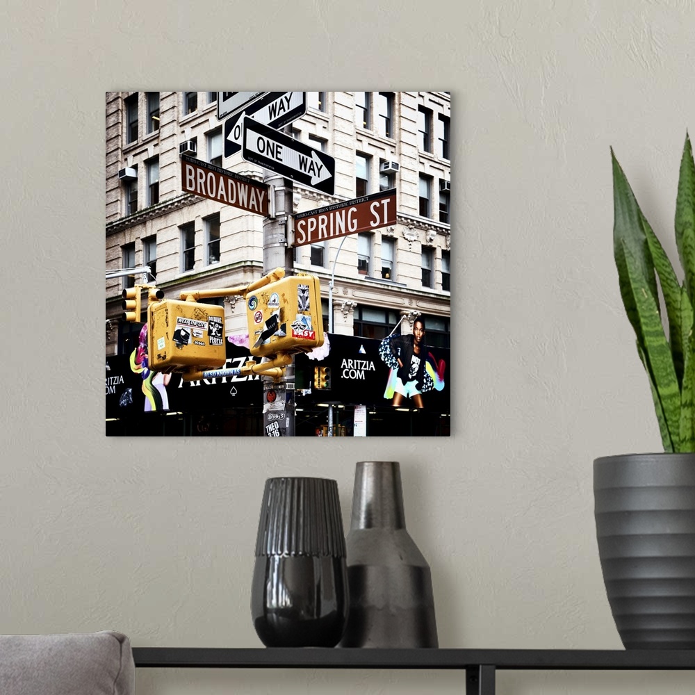 A modern room featuring Post with one way signs and Broadway and Spring Street signs, with stickers and graffiti on the l...