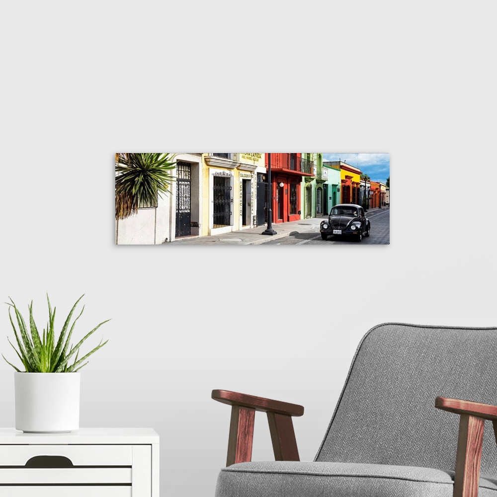 A modern room featuring Panoramic photograph of a classic black Volkswagen Beetle driving up a colorful street in Mexico....