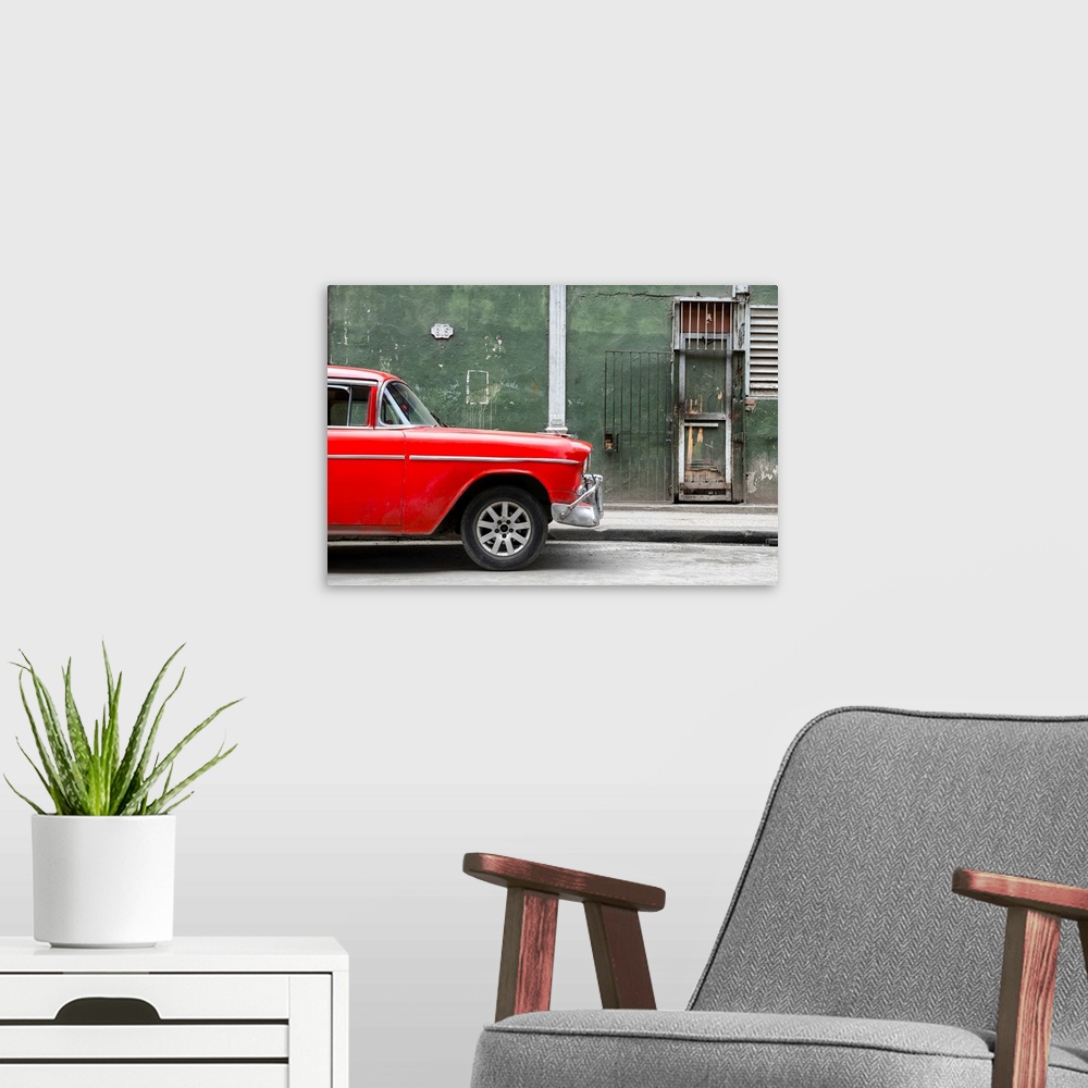 A modern room featuring Photograph of the front of a bright red vintage car with a dark green building in the background ...