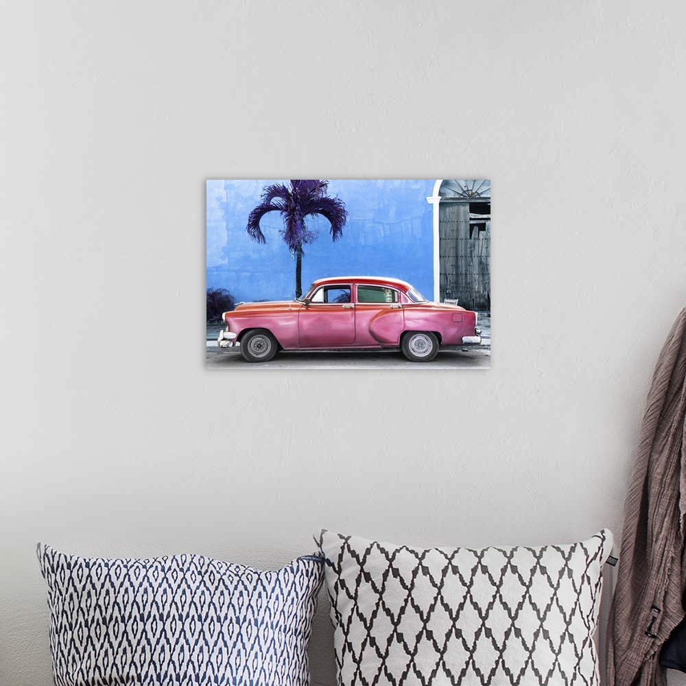A bohemian room featuring Photograph of a pink vintage car parked outside of a blue building with a palm tree.