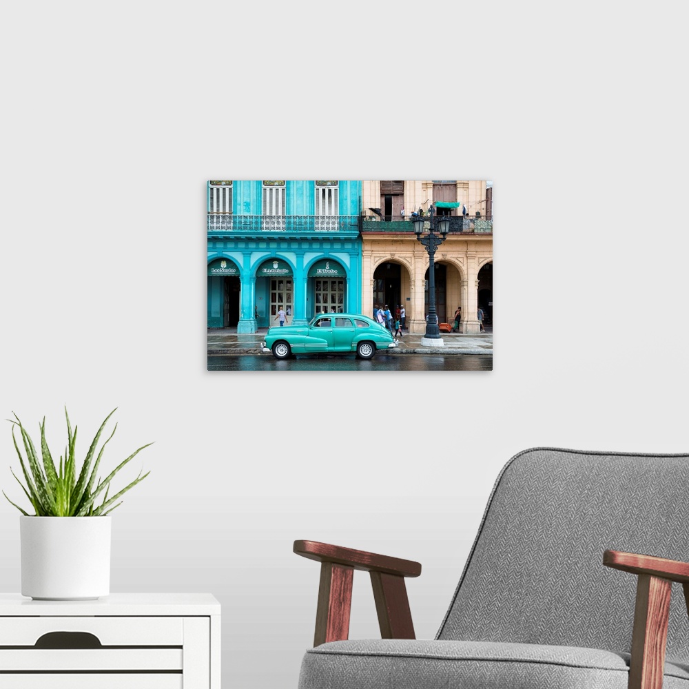 A modern room featuring Photograph of a turquoise vintage car parked outside of a bright blue building in downtown Havana.