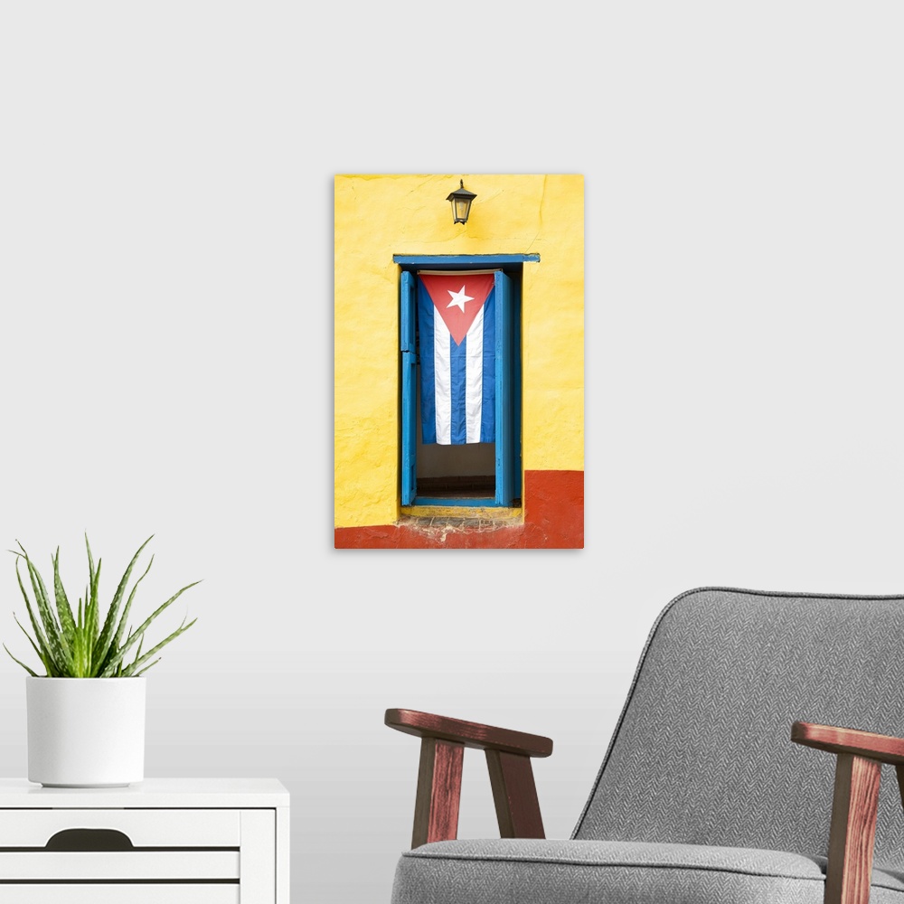 A modern room featuring Photograph of the Cuban flag hanging in a window on a yellow and red wall in Havana.