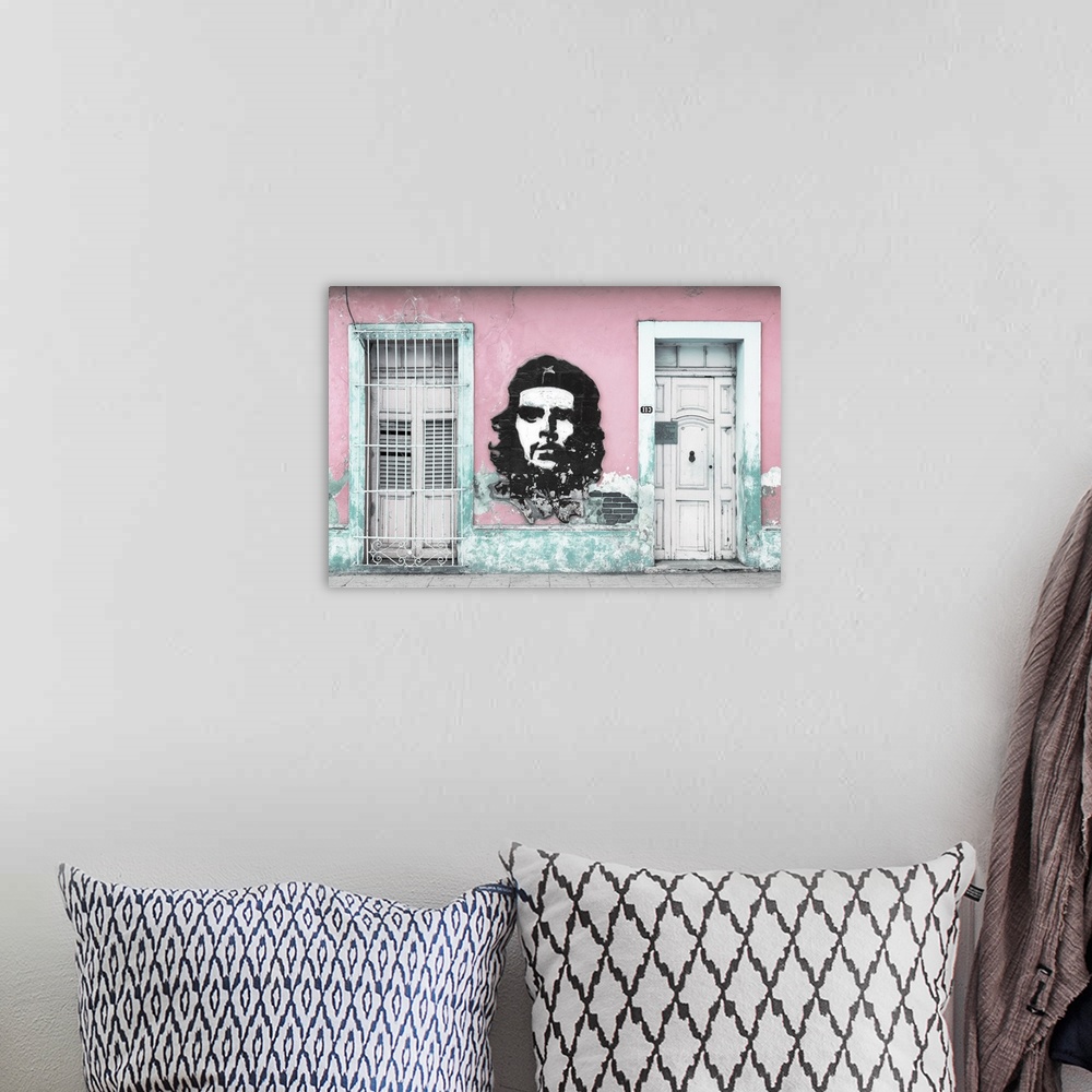 A bohemian room featuring Photograph of a Cuban facade with Che Guevara painted in between a window and a door on a pink wall.