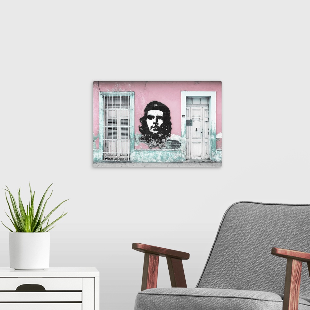 A modern room featuring Photograph of a Cuban facade with Che Guevara painted in between a window and a door on a pink wall.