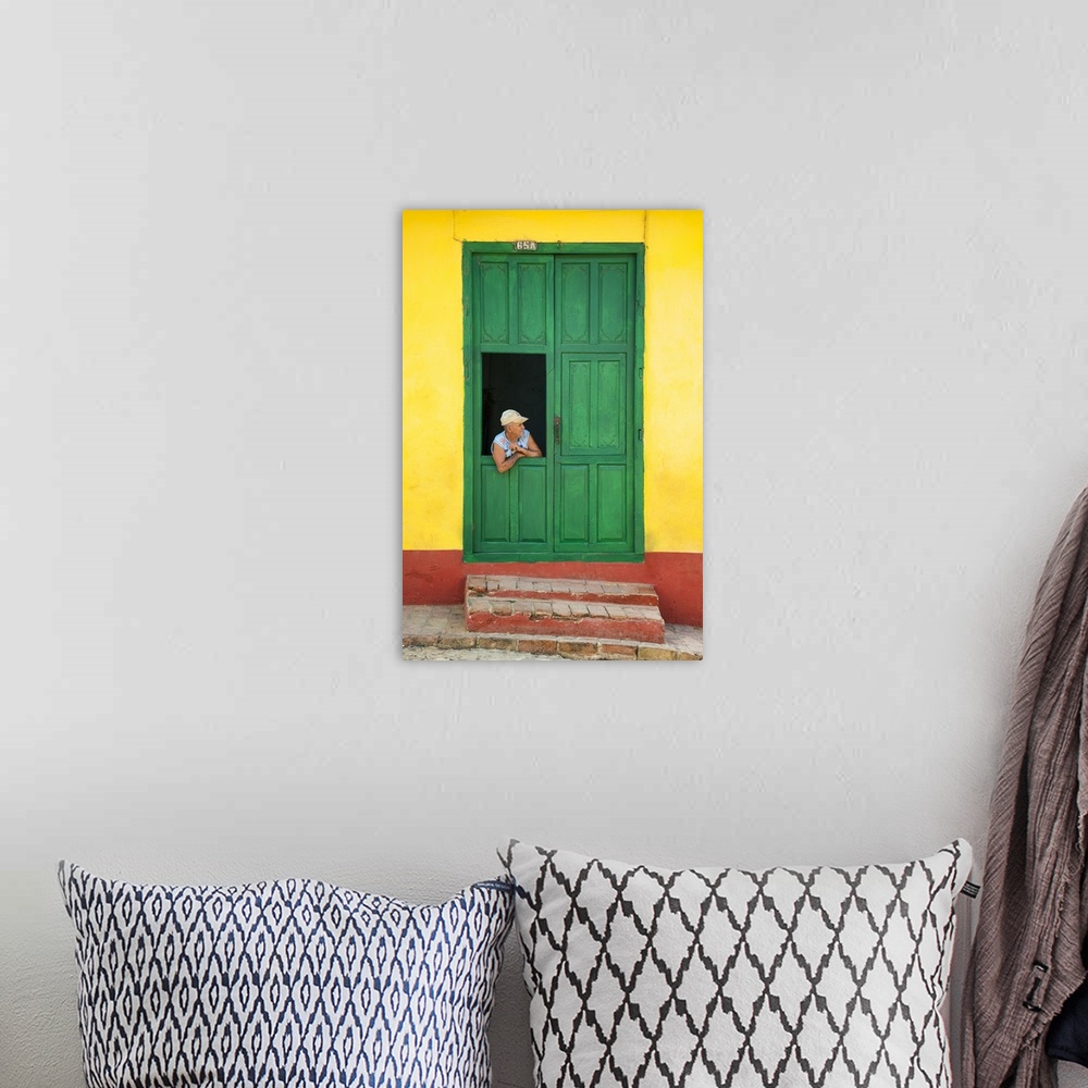 A bohemian room featuring Photograph of a man leaning through a window connected to a large green door on a yellow and red ...