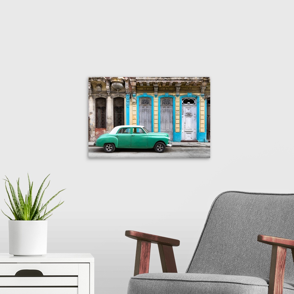 A modern room featuring Photograph of a green vintage car with a white roof parked on the street in front of a blue and y...