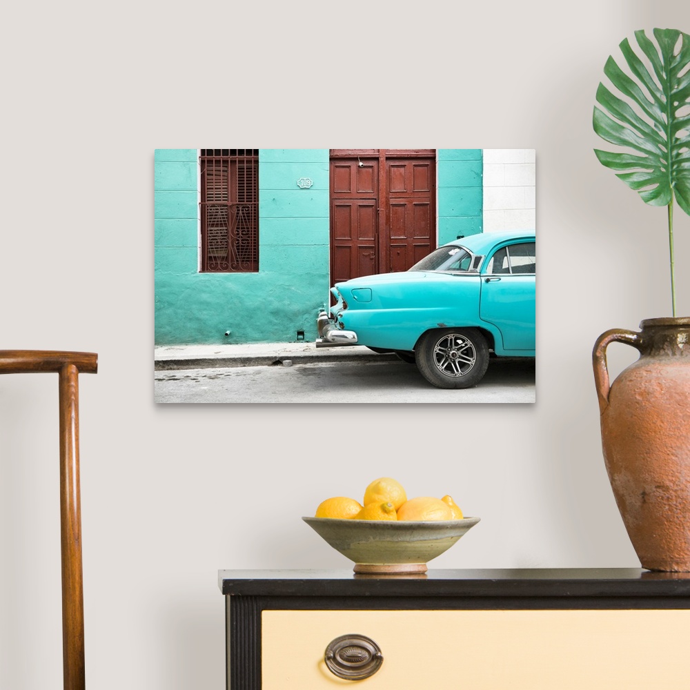 A traditional room featuring Photograph of the back of a turquoise vintage car next to a matching facade with a dark wooden do...