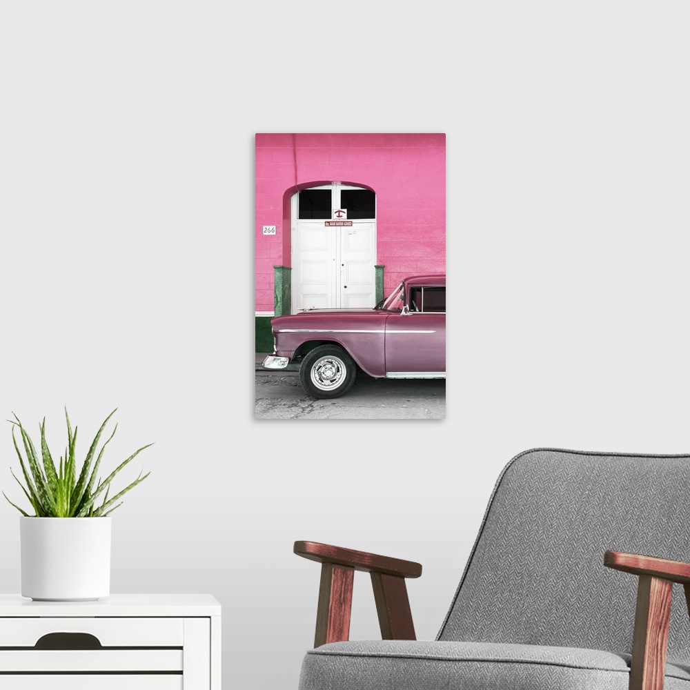 A modern room featuring Vintage pink car parked in front of a pink facade with a white door.