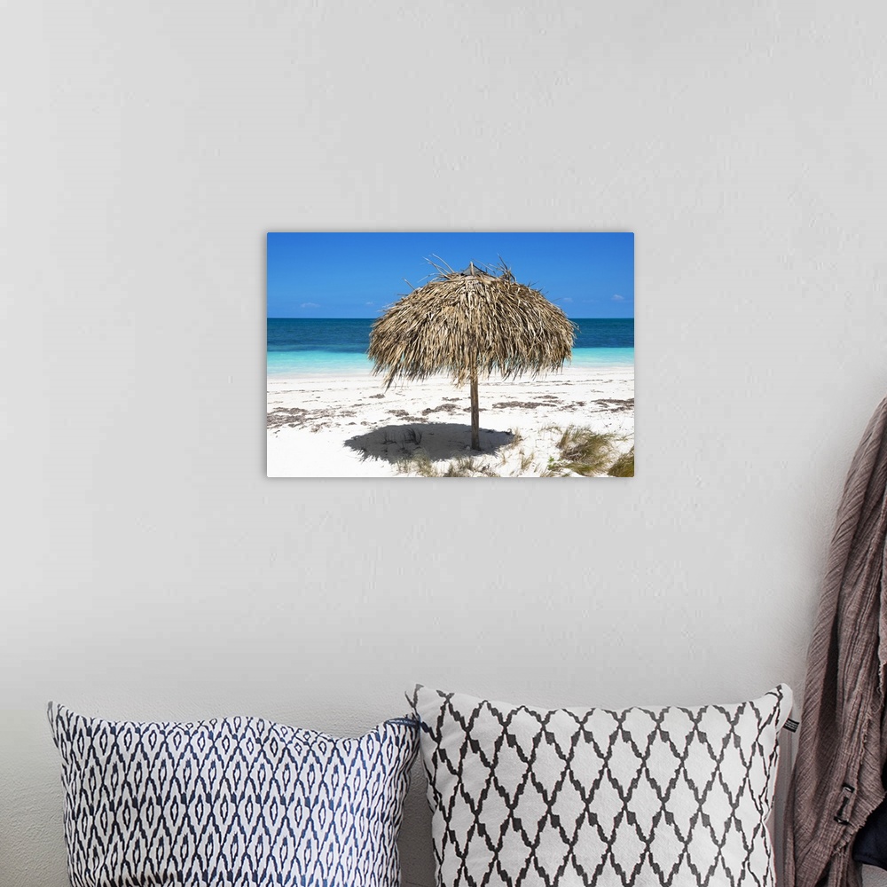 A bohemian room featuring Photograph of an umbrella made with natural materials on a beautiful beach in Cuba.