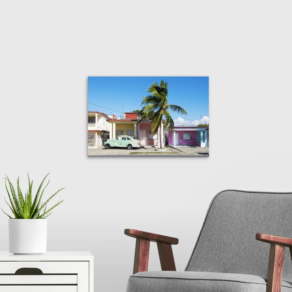 A modern room featuring Photograph of an old car parked in font of a house in Cuba.