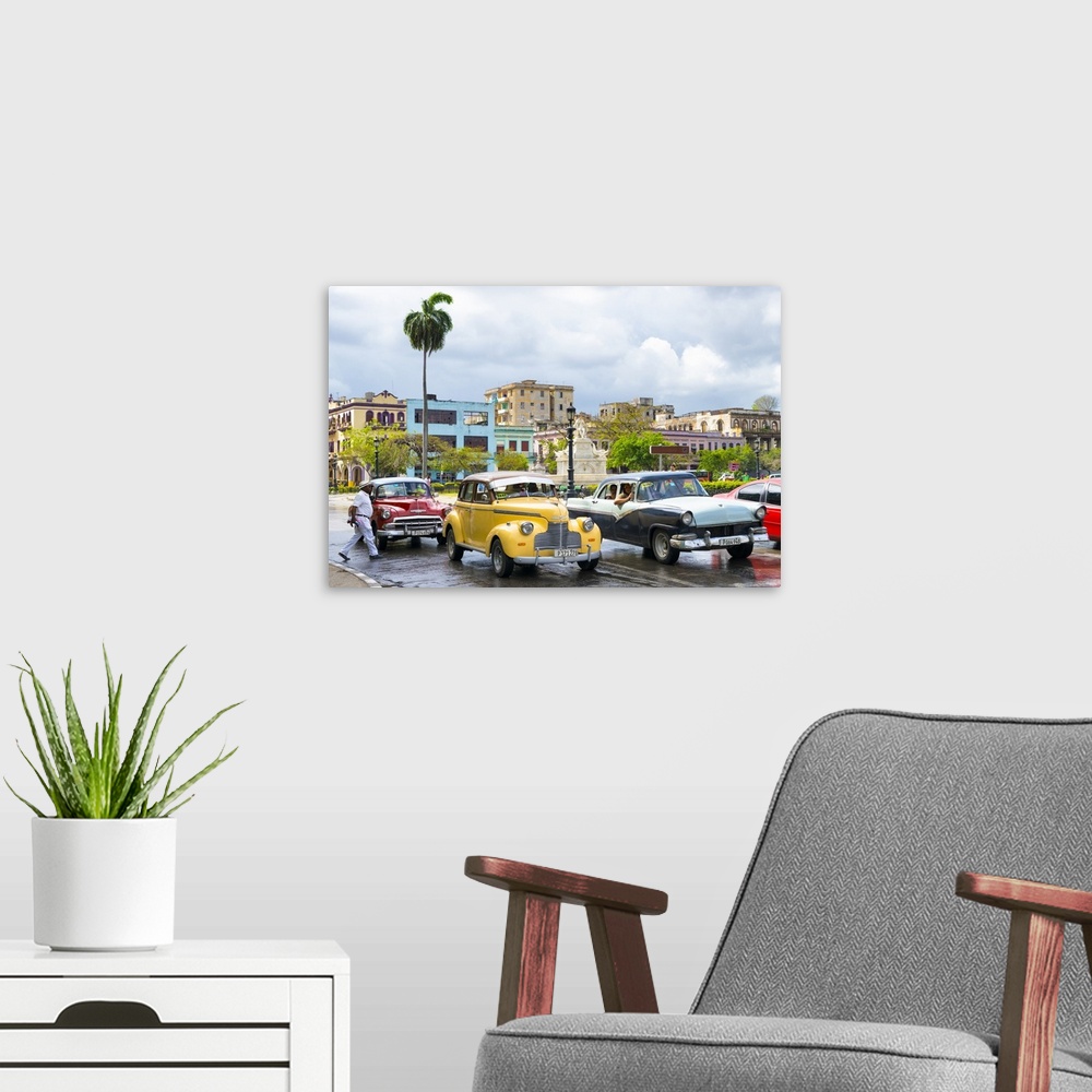 A modern room featuring Photograph of a cloudy sky above a wet Havana street scene with vintage cars and taxis.