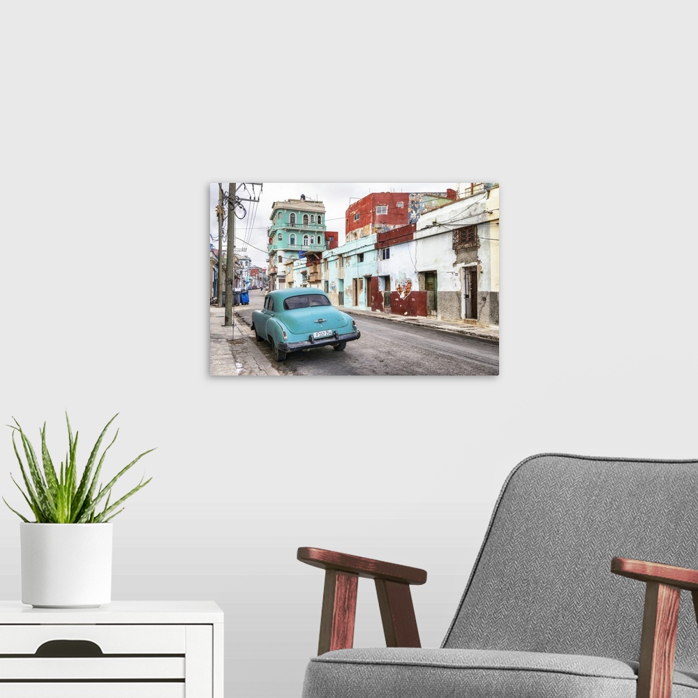 A modern room featuring Photograph of a vintage turquoise car parked in the street surrounded by worn buildings in Havana...