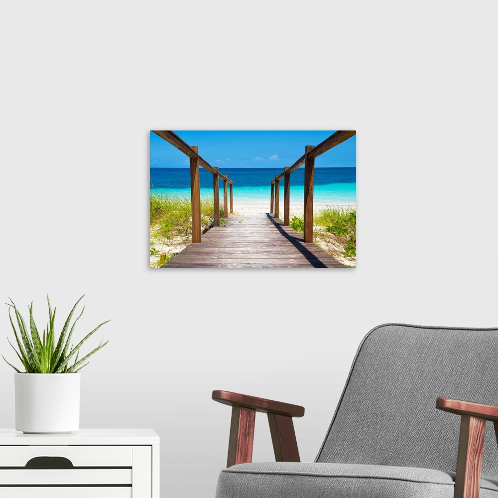 A modern room featuring Photograph of a wooden walkway leading straight to the white sands and crystal blue waters of a b...