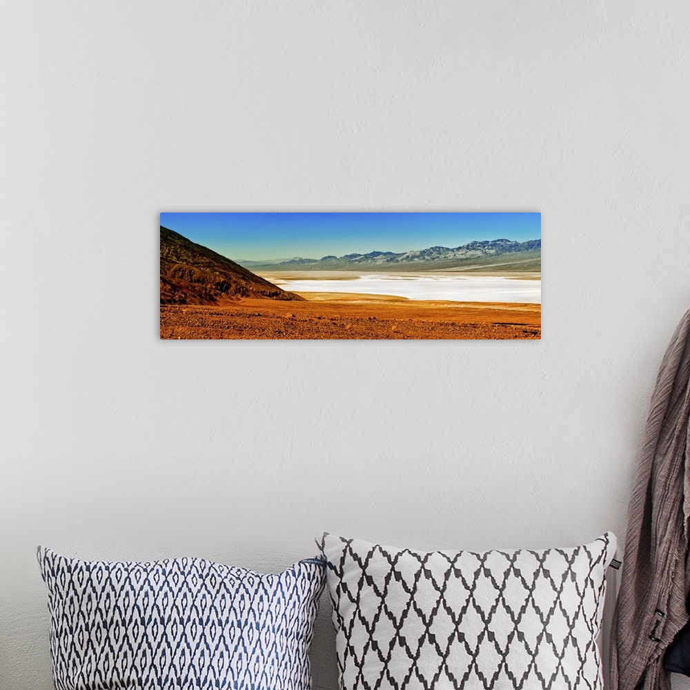 A bohemian room featuring Photo of the Death Valley desert landscape, a flat plain bordered by low mountains.