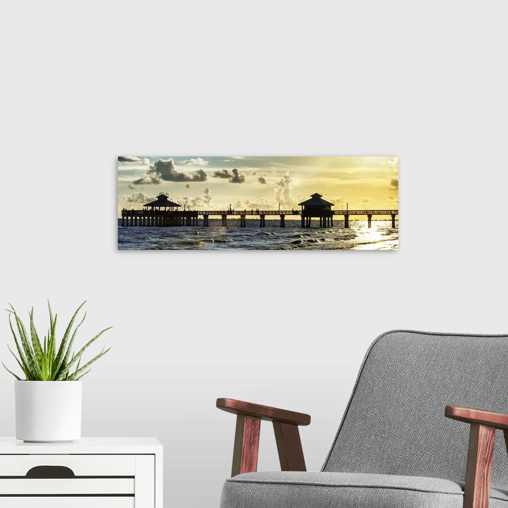 A modern room featuring Panoramic view of a silhouetted fishing pier at sundown in Florida.