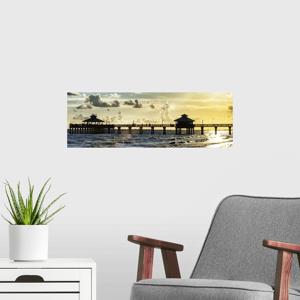 A modern room featuring Panoramic view of a silhouetted fishing pier at sundown in Florida.