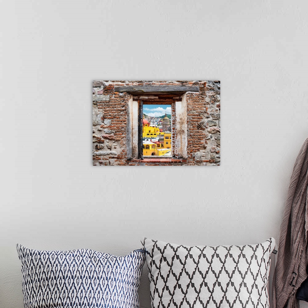 A bohemian room featuring View of the colorful city of Guanajuato framed through a stony, brick window. From the Viva Mexic...