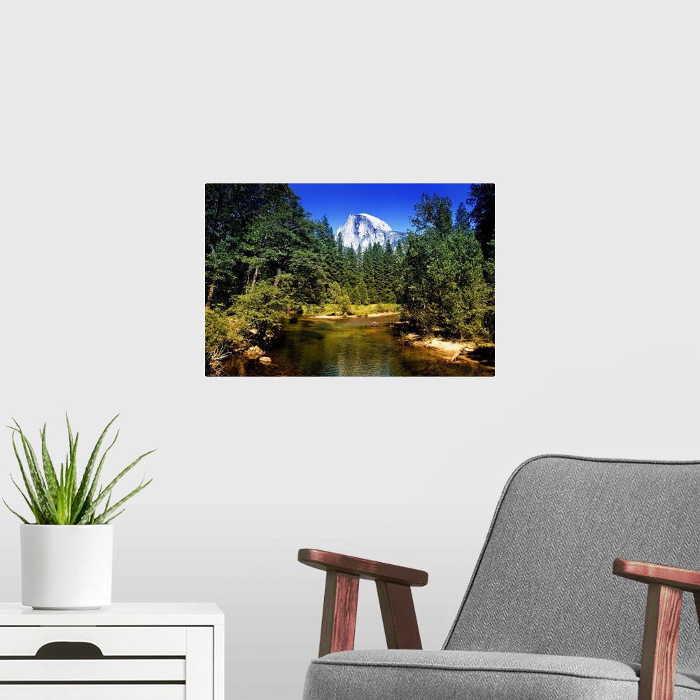A modern room featuring The peak of Half Dome can be seen over the tops of pine trees in California's Yosemite National P...