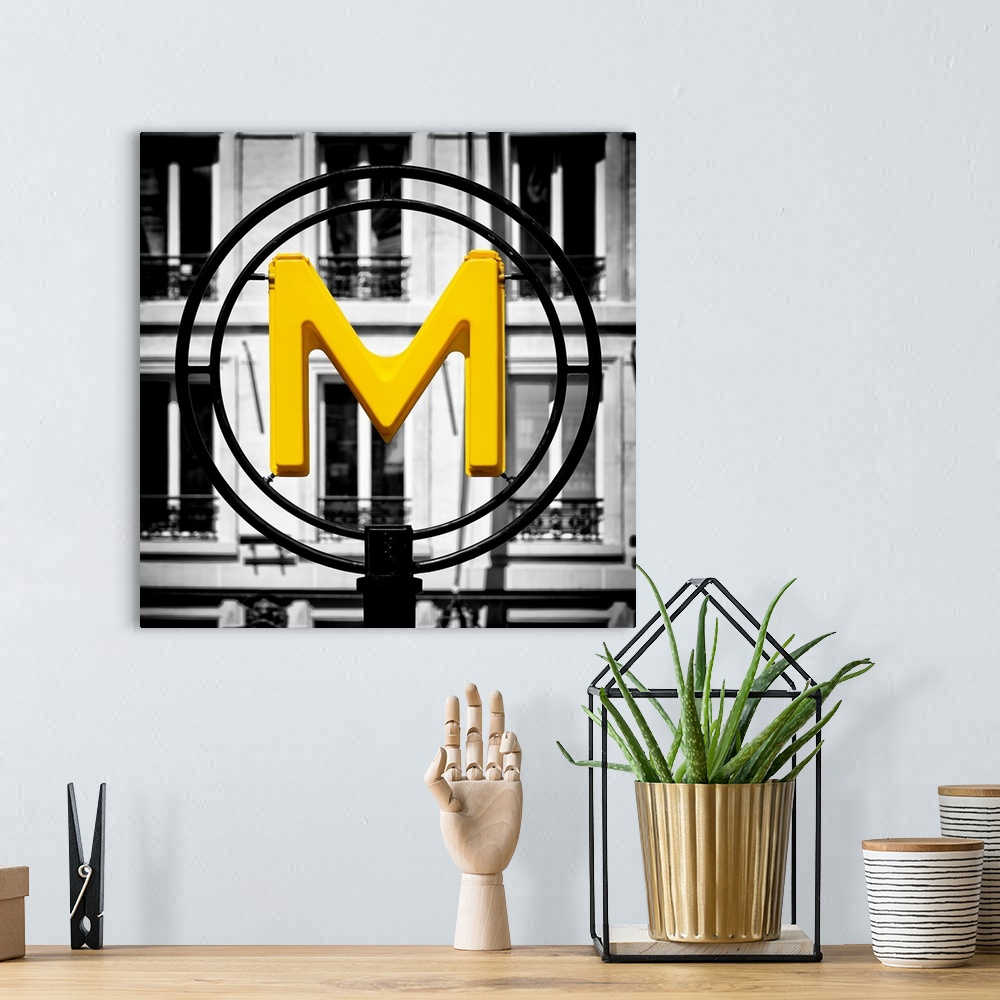 A bohemian room featuring An artistic photograph of a bright yellow M for metro sign against a completely black and white e...