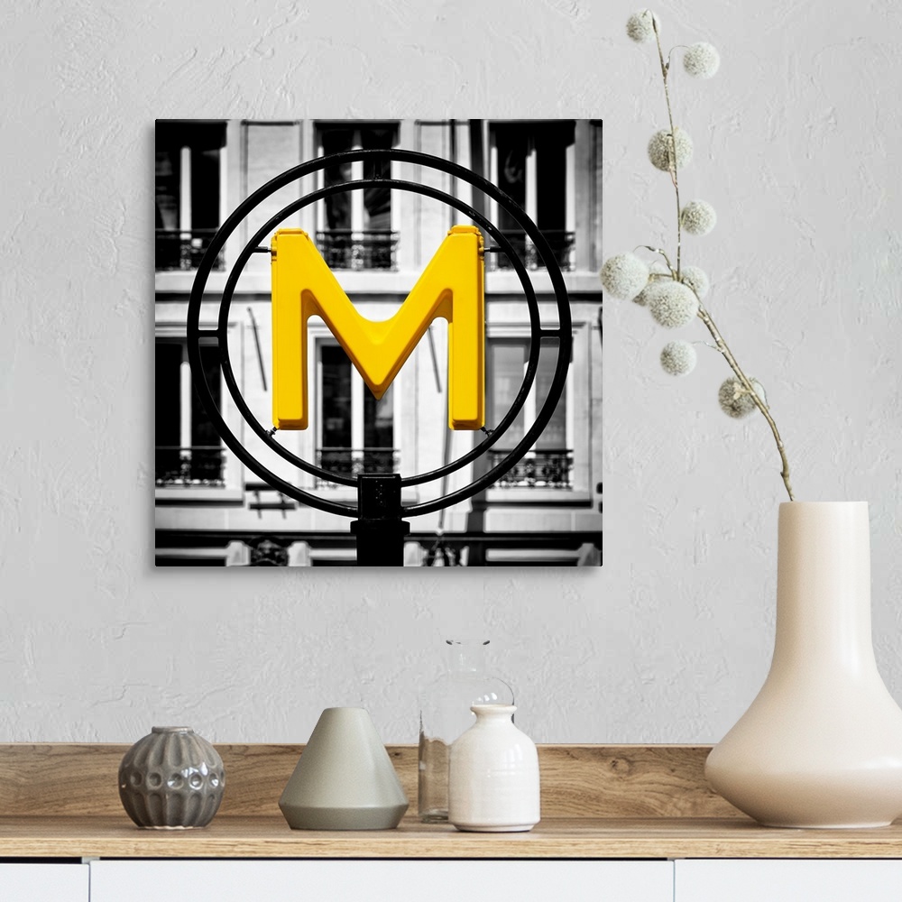 A farmhouse room featuring An artistic photograph of a bright yellow M for metro sign against a completely black and white e...