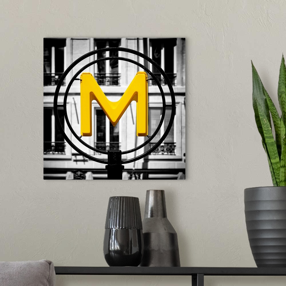 A modern room featuring An artistic photograph of a bright yellow M for metro sign against a completely black and white e...