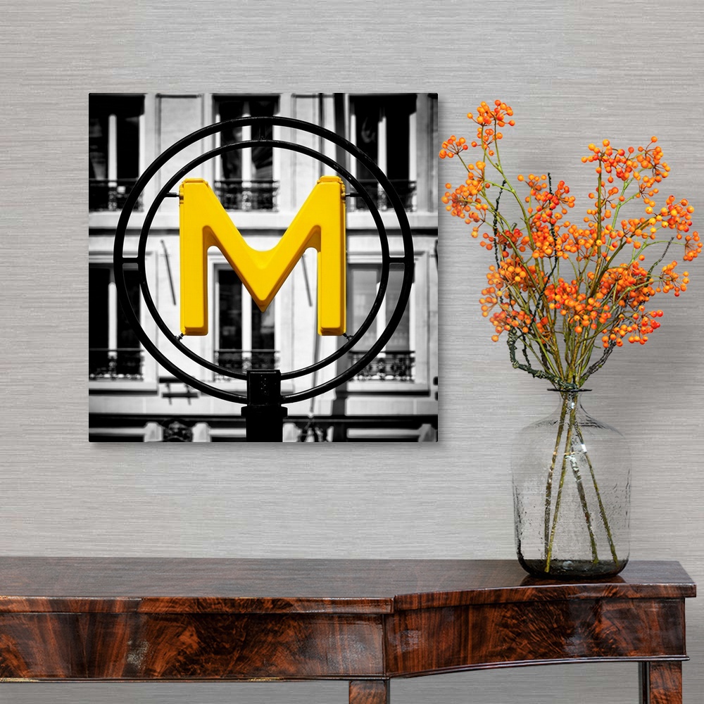 A traditional room featuring An artistic photograph of a bright yellow M for metro sign against a completely black and white e...