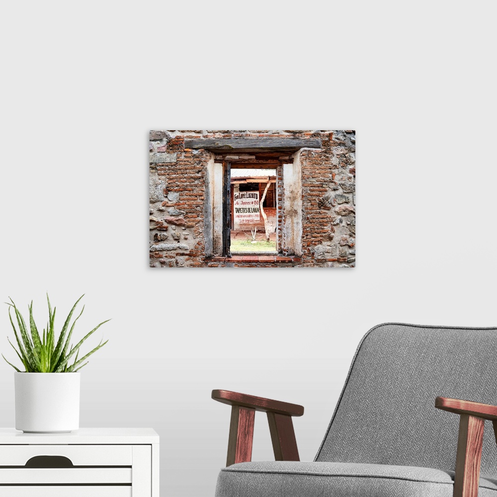 A modern room featuring View of a woven rug manufacturer building in Mexico framed through a stony, brick window. From th...