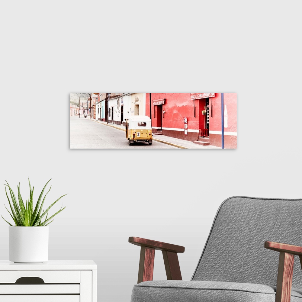 A modern room featuring Panoramic photograph of a street scene in Mexico with a yellow tuck tuk (taxi) driving up the roa...