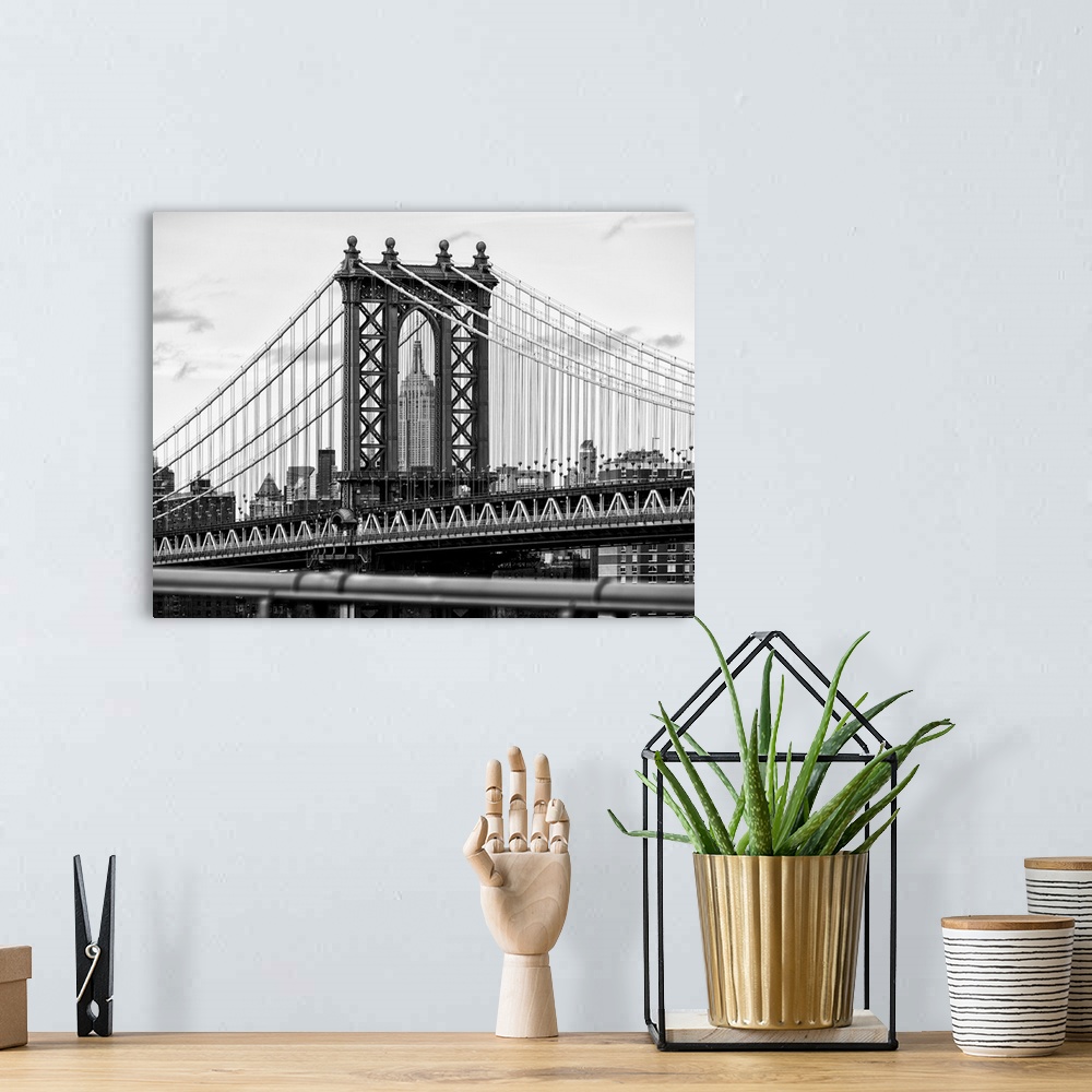A bohemian room featuring A black and white photograph of the Manhattan bridge, with the Empire state building in the backg...