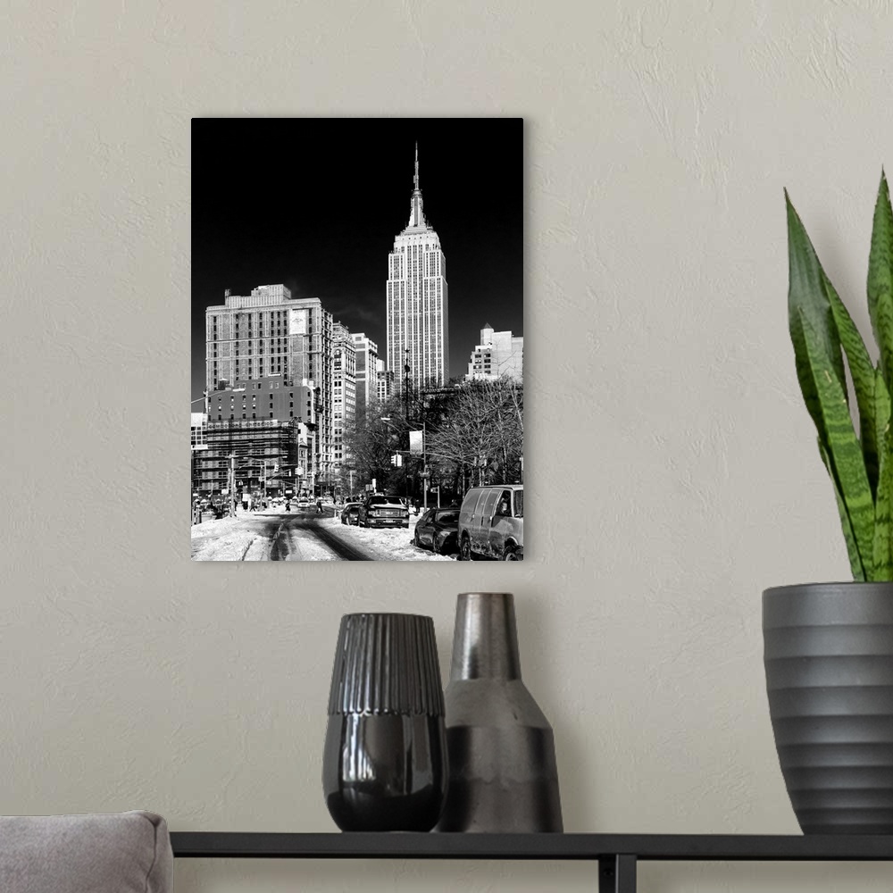 A modern room featuring A black and white photograph of the Empire state building standing tall in NYC, seen from street ...