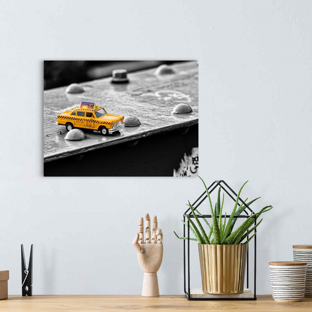 A bohemian room featuring A photograph of a toy taxi cab sitting on a steel beam on the Brooklyn bridge.