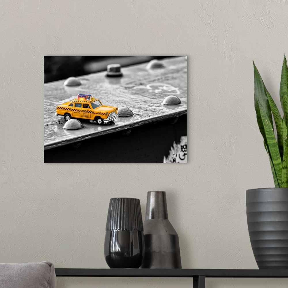 A modern room featuring A photograph of a toy taxi cab sitting on a steel beam on the Brooklyn bridge.