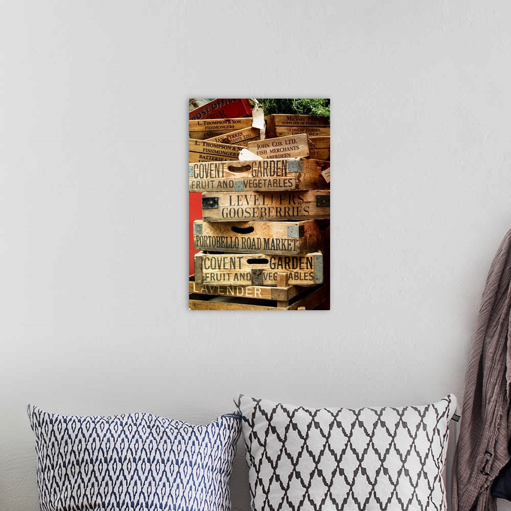 A bohemian room featuring A stack of weathered wooden crates with names of markets lettered on the sides.