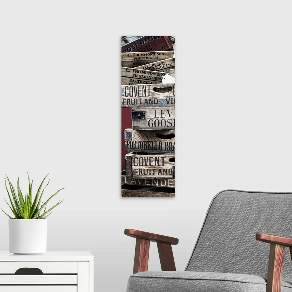 A modern room featuring A stack of weathered wooden crates with names of markets lettered on the sides.