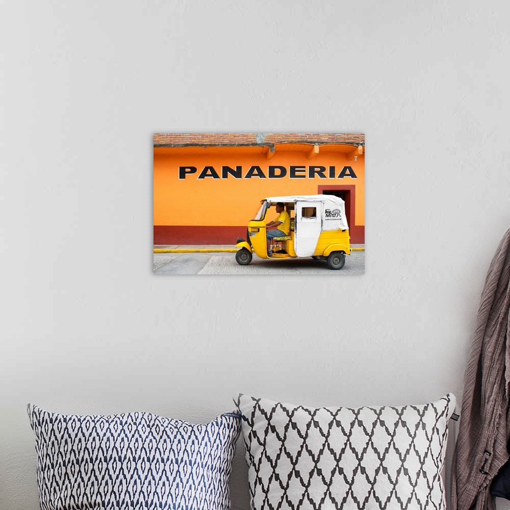 A bohemian room featuring Photograph of a yellow Tuk Tuk (taxi) driving on the street in front of a bakery with orange exte...