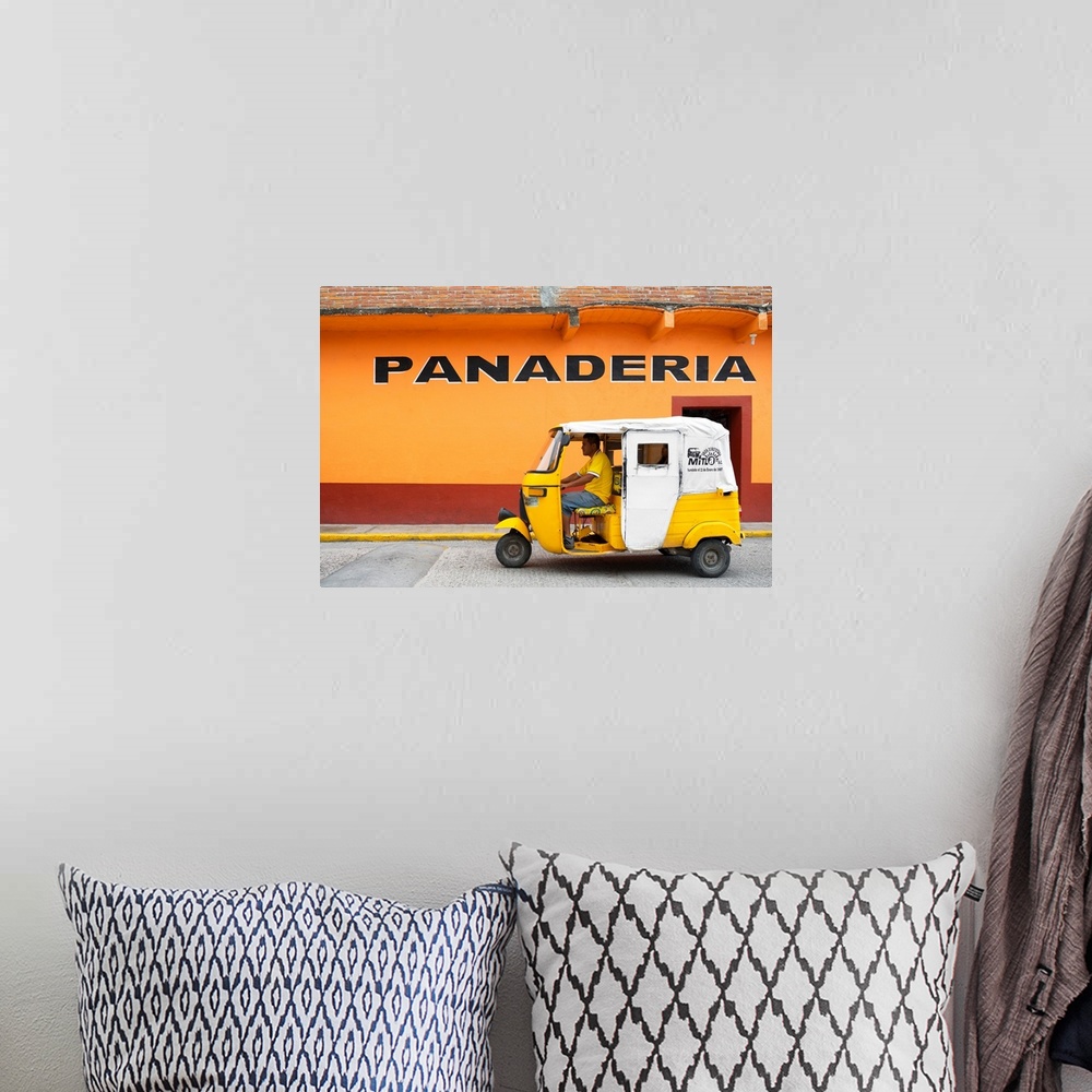 A bohemian room featuring Photograph of a yellow Tuk Tuk (taxi) driving on the street in front of a bakery with orange exte...