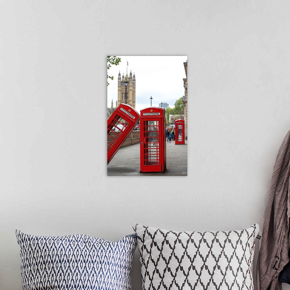 A bohemian room featuring Three red phone booths, one leaning against the other, with the House of Parliament in the backgr...