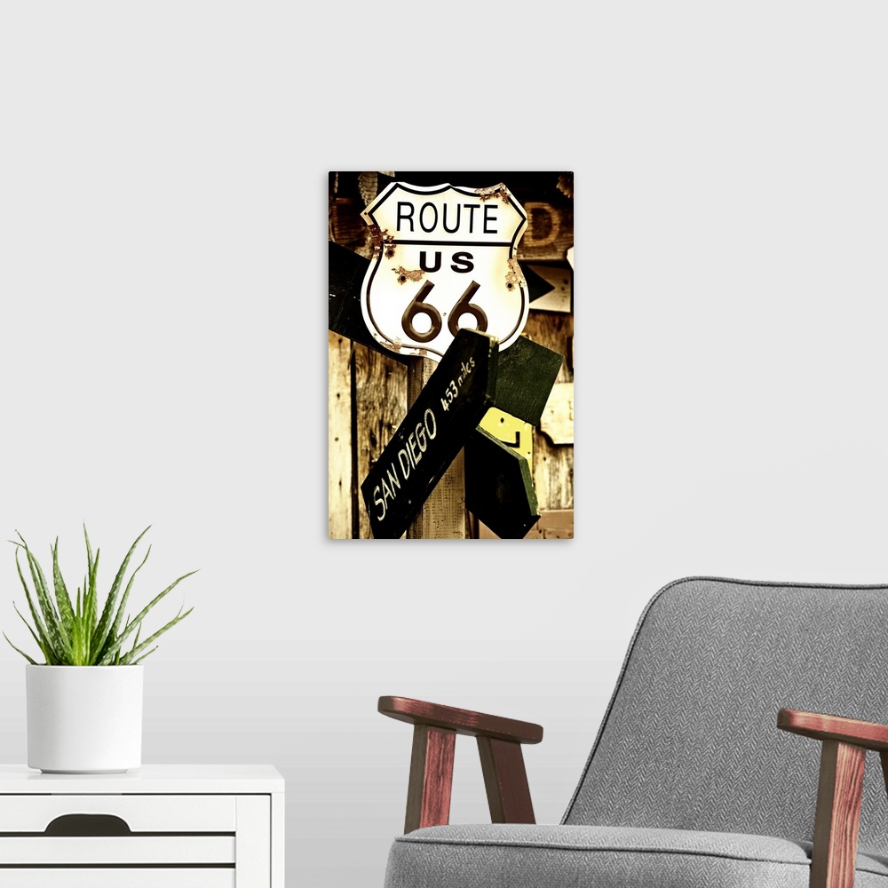 A modern room featuring A rusted metal sign for Route 66 and a direction sign pointing towards San Diego.