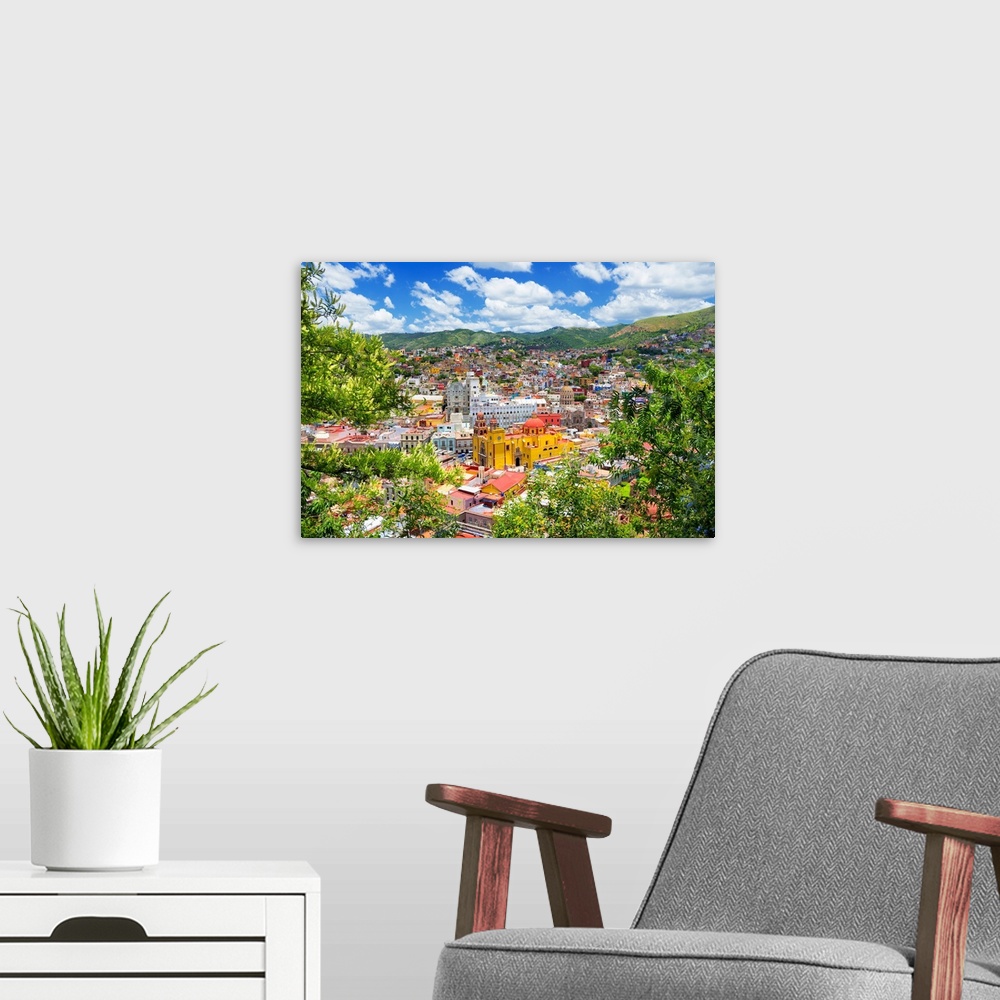 A modern room featuring Aerial photograph of a colorful cityscape in Guanajuato, mexico, framed by lush, green trees. Fro...
