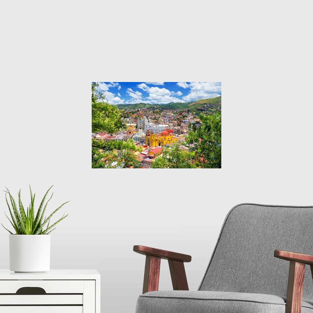 A modern room featuring Aerial photograph of a colorful cityscape in Guanajuato, mexico, framed by lush, green trees. Fro...