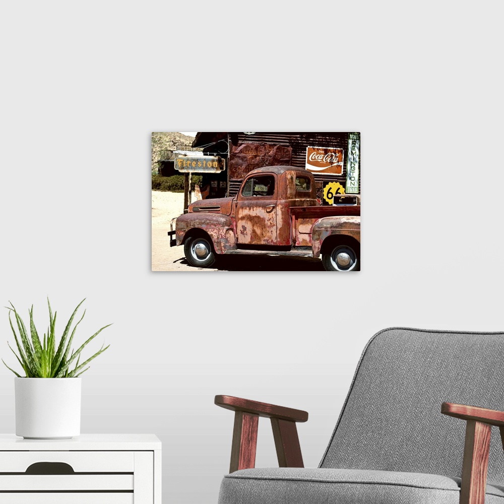 A modern room featuring A very rusty pickup truck sits by a weathered gas station on Route 66.