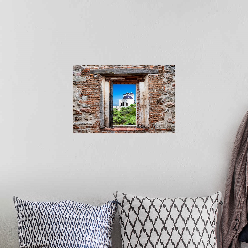 A bohemian room featuring View of a white house in Isla Mujeres, Mexico, framed through a stony, brick window. From the Viv...
