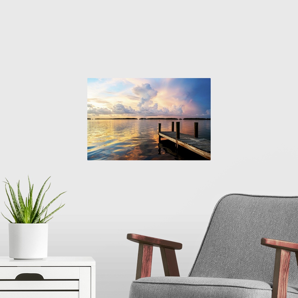 A modern room featuring A dock reaching out into the ocean at twilight with stunning clouds.