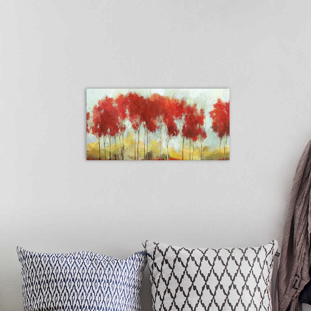 A bohemian room featuring A long horizontal painting of a row of trees with bright red leaves in the fall.