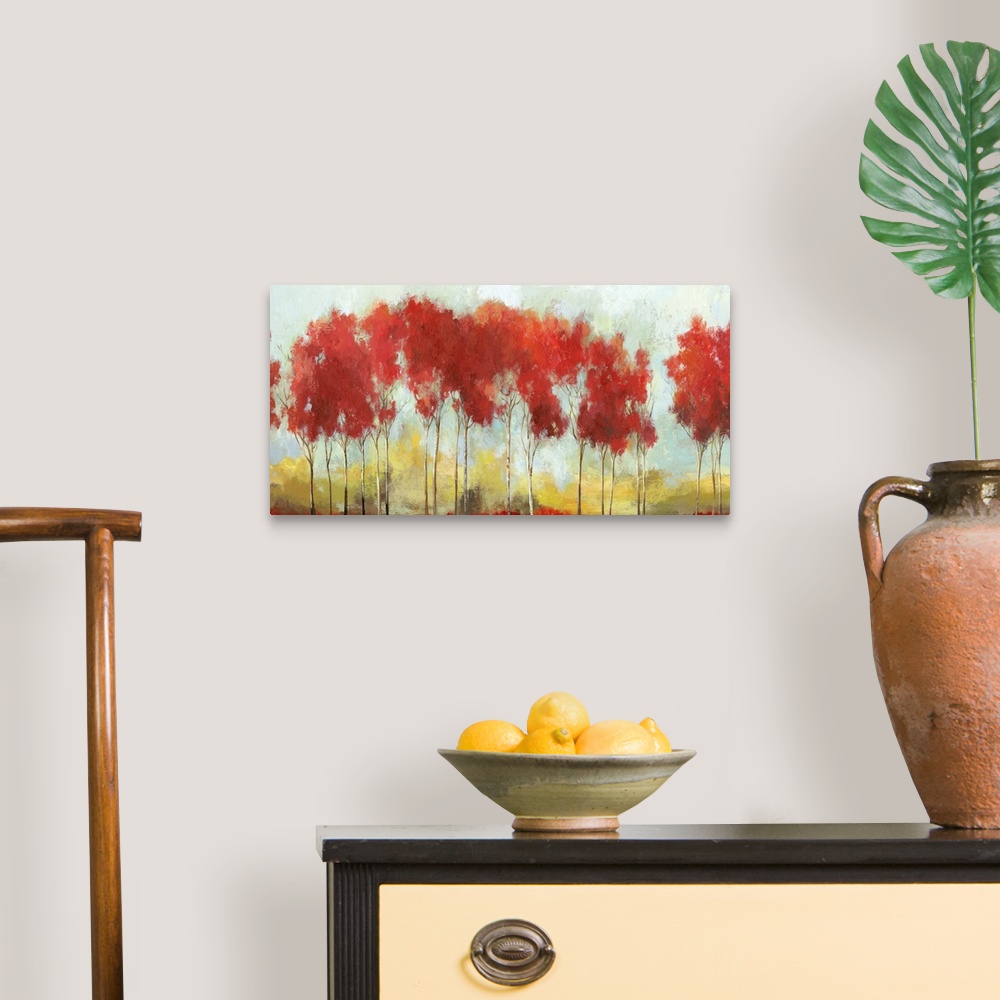 A traditional room featuring A long horizontal painting of a row of trees with bright red leaves in the fall.