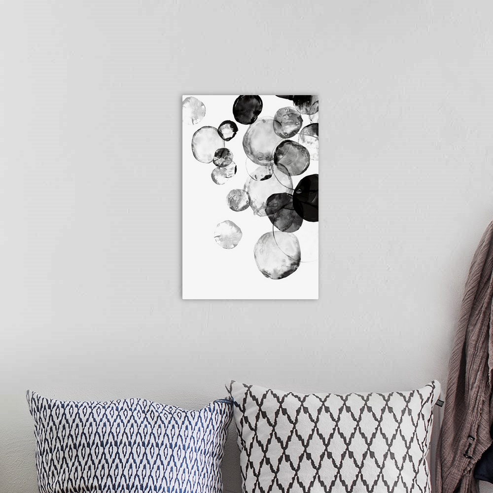A bohemian room featuring Large vertical painting of black circular shapes on white.