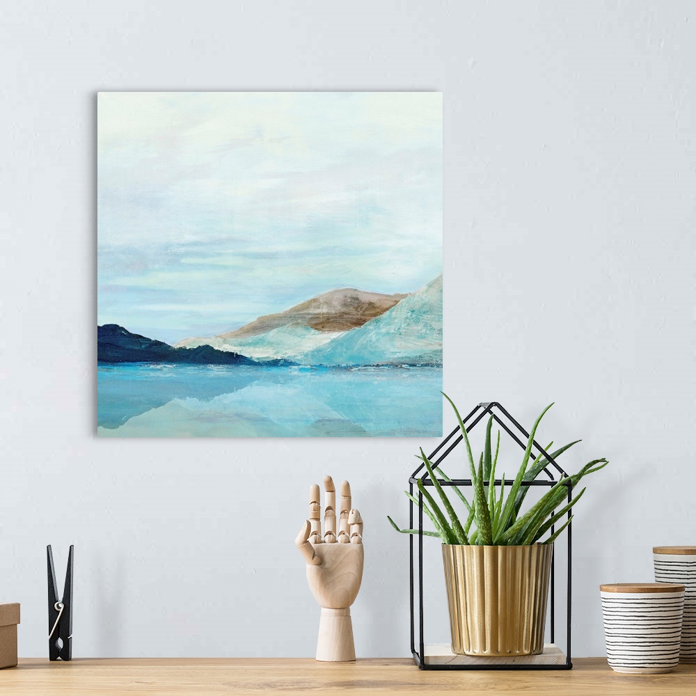 A bohemian room featuring Square painting of rolling mountains along a lake with a clear blue sky.
