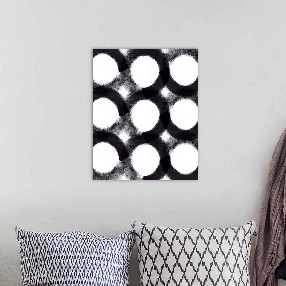 A bohemian room featuring A vertical painting of circles with black brush strokes.